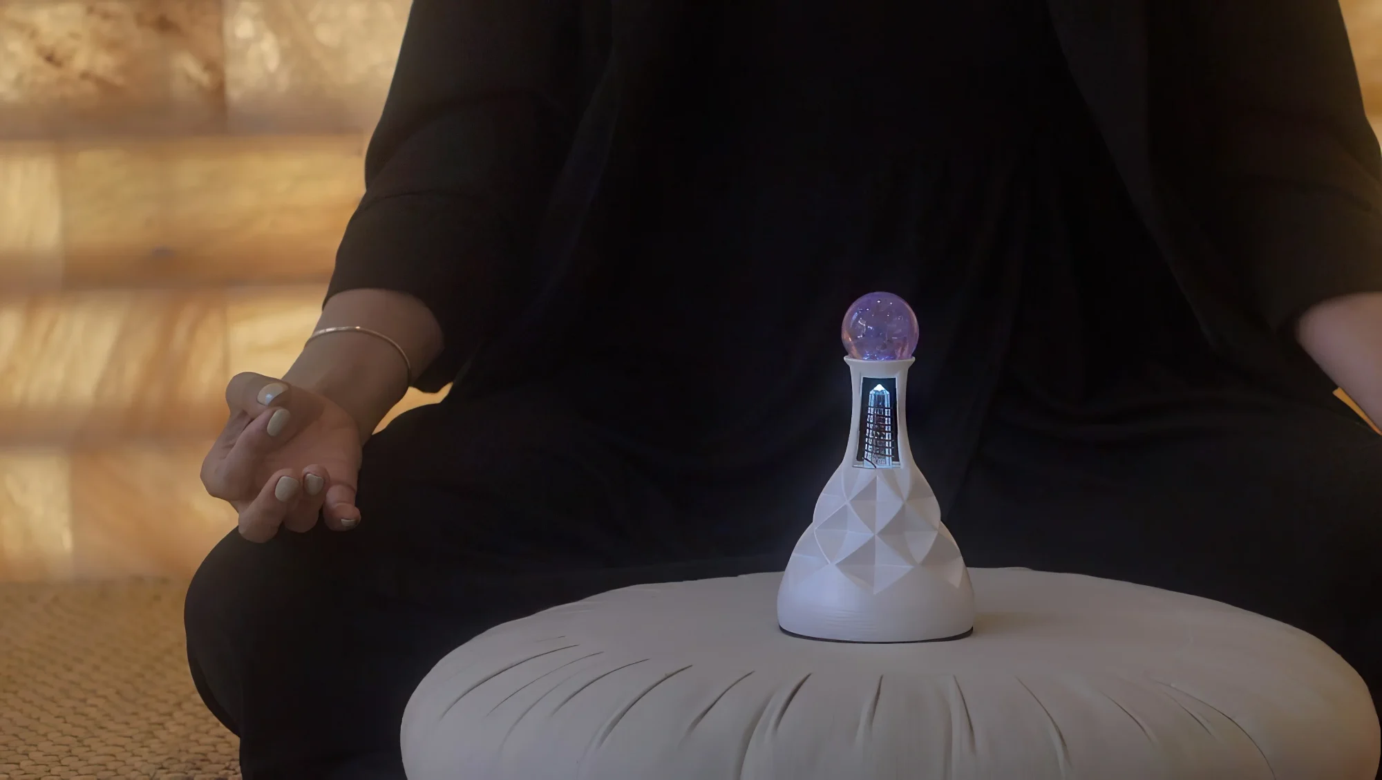 A practitioner seated in meditation beside the Living Crystal, its sphere lit softly from within